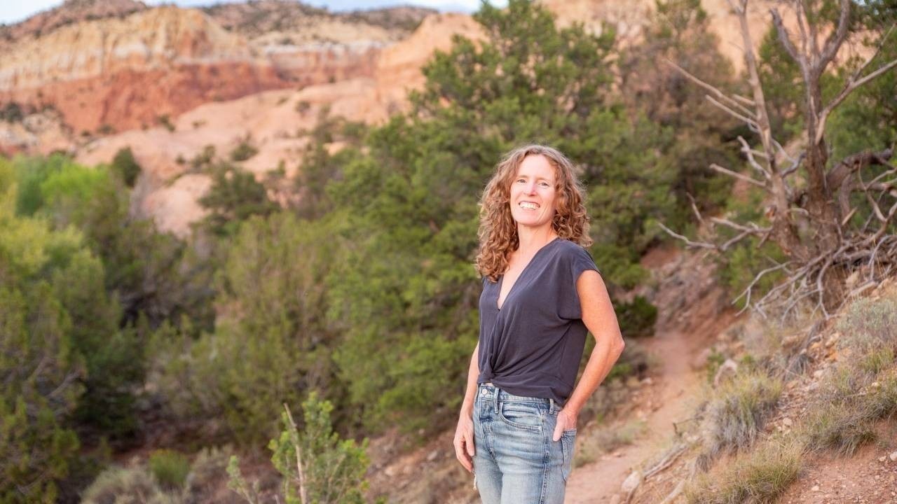 Woman smiling and holding her left hand in her jean pocket in nature