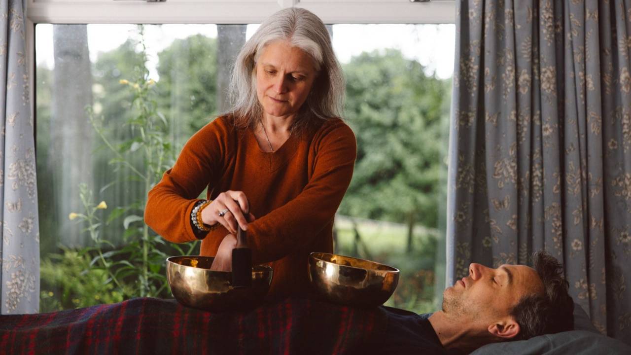 Blonde woman sitting down next to sound healing instruments