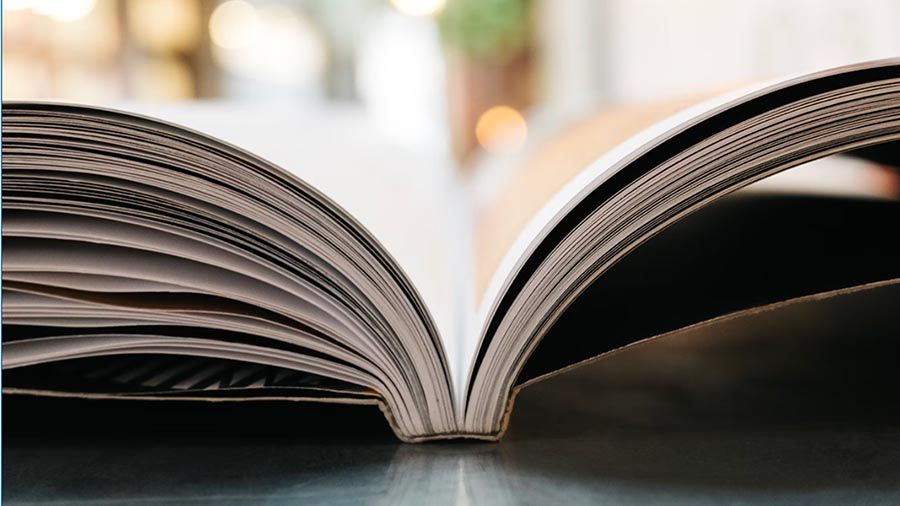 A stack of books with one on top opened at the world's map in a library