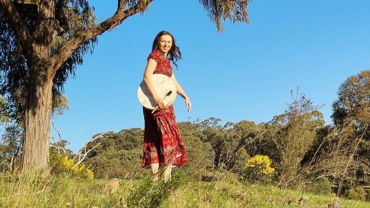 Woman in a red dress in nature, holding a drum 
