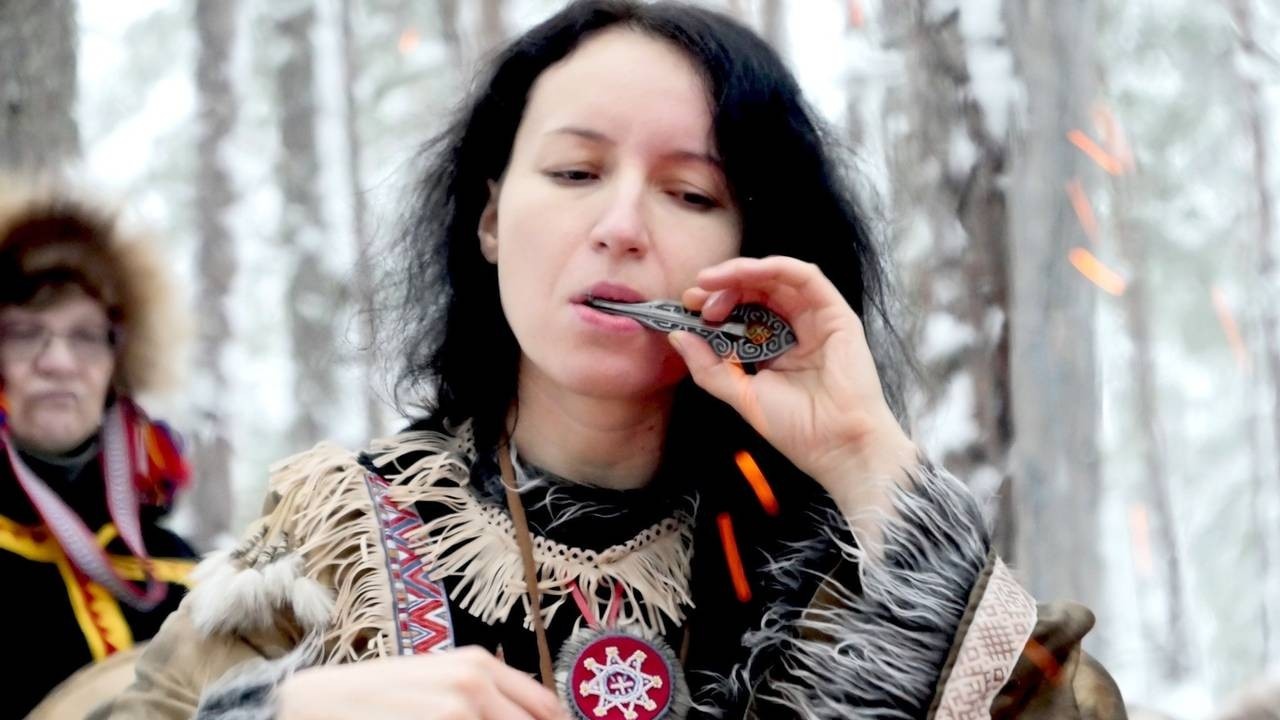 Brunette woman playing a small flute outdoors in the winter