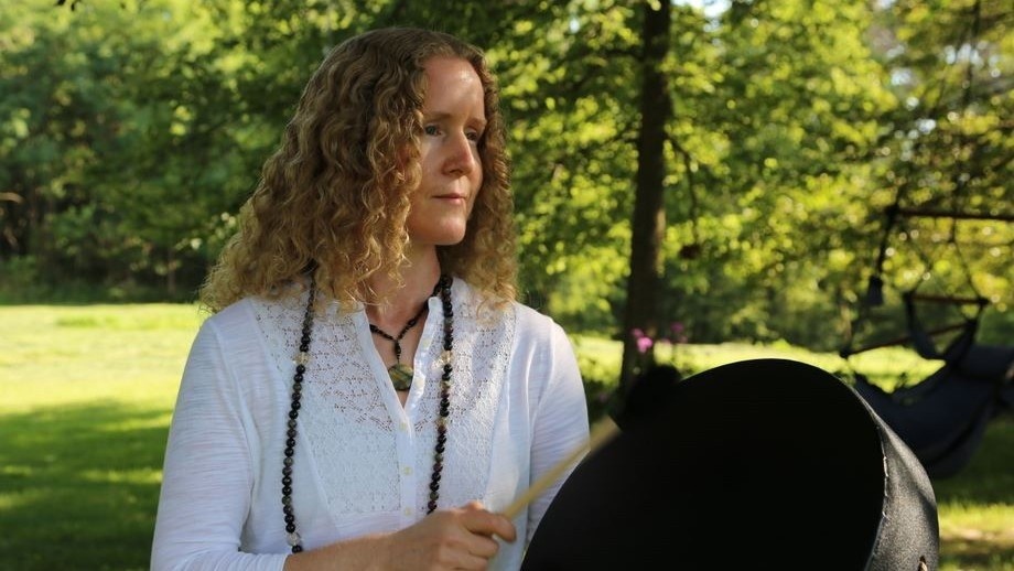 woman holding a black shamanic drum in nature