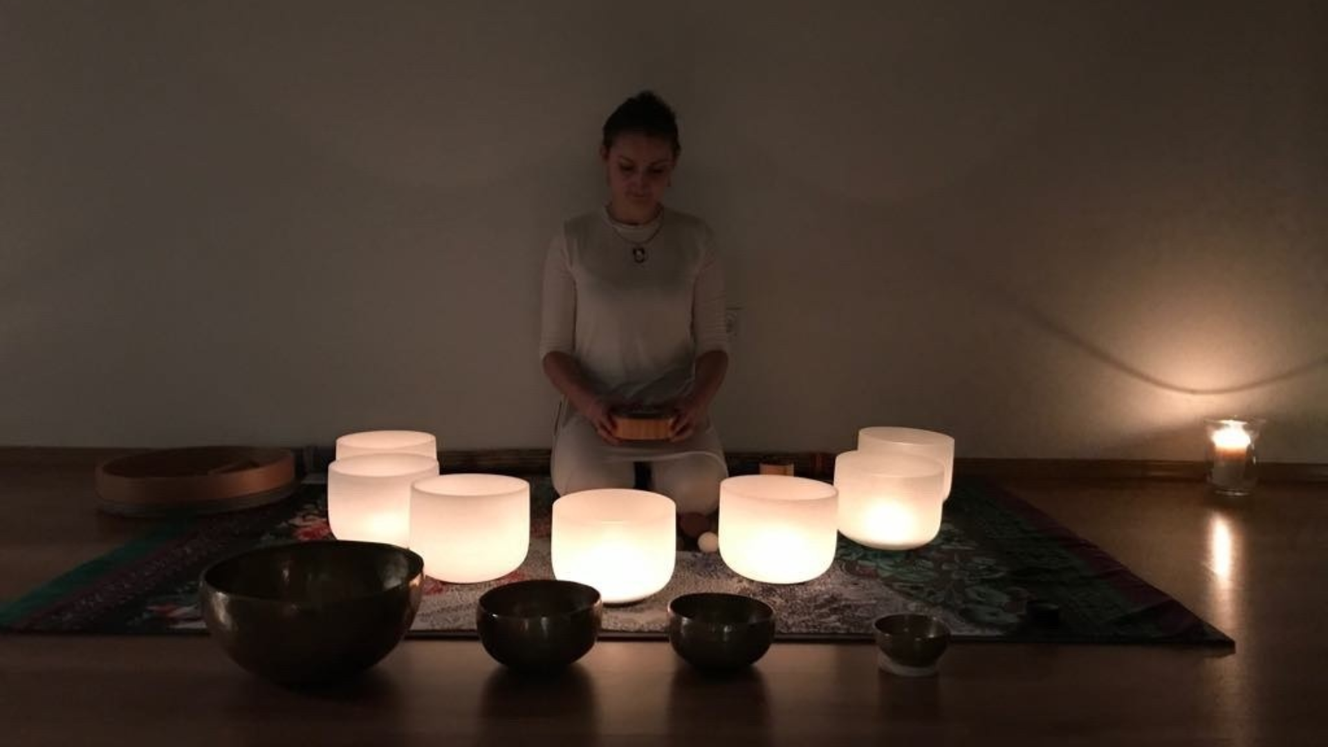Woman with many tibetan singing bowls lied on the floor behind her